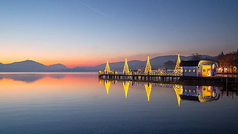 Der Wörthersee mit beleuchteten Häusern in der Abenddämmerung 