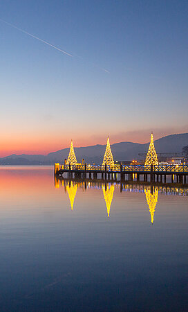 Der Wörthersee mit beleuchteten Häusern in der Abenddämmerung 