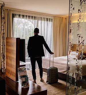 Mann mit Koffer im Deluxe Zimmer