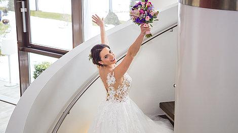 Frau im Hochzeitskleid schreitet die Stiege nach oben
