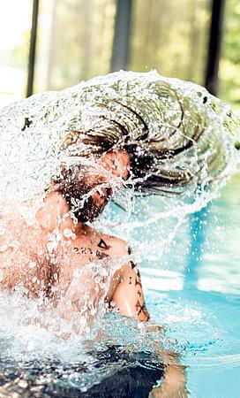 Mann taucht aus dem Pool auf 